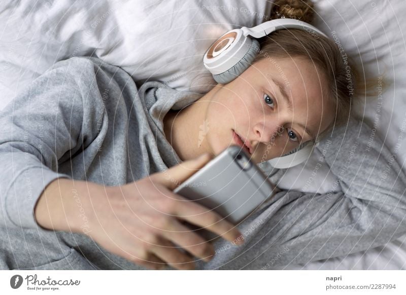 Chill in perfection Feminine Young woman Youth (Young adults) 1 Human being 13 - 18 years Headphones Cellphone Relaxation Listening Lie Authentic Gray White