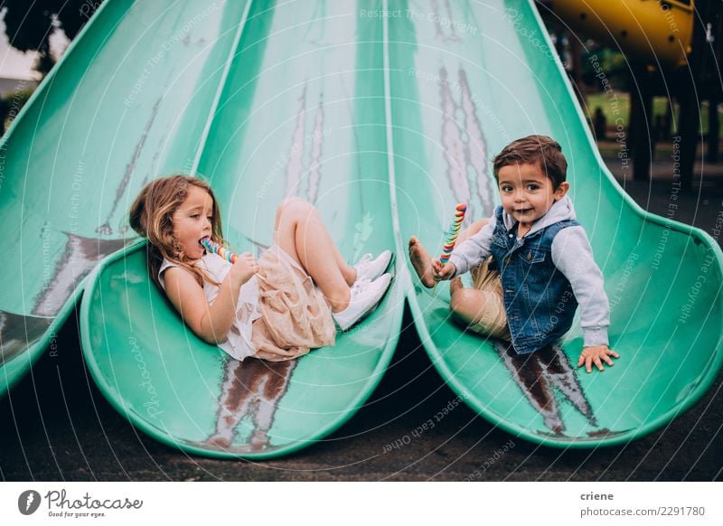 Cute caucasian siblings sitting on slide on playground Eating Joy Happy Boy (child) Sister Family & Relations Infancy Playground Smiling brother sweets