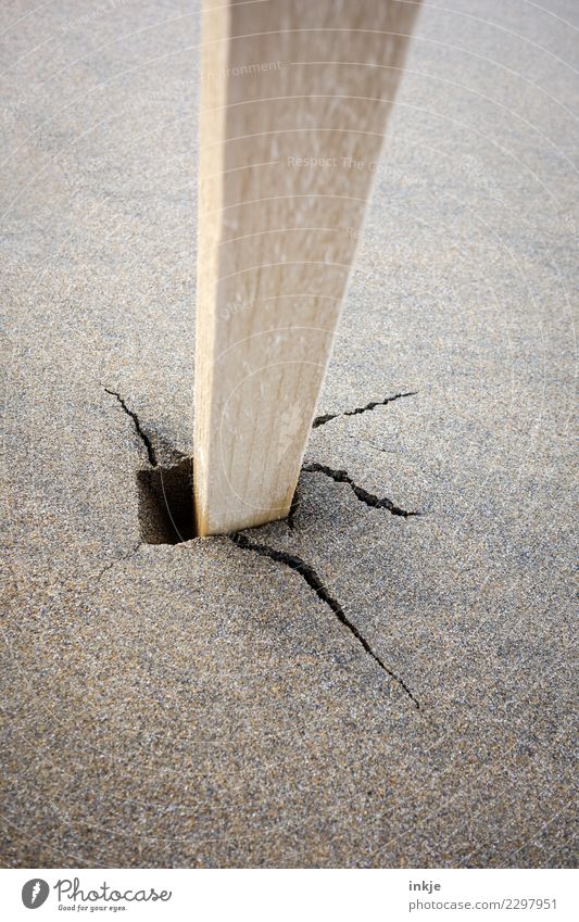 Unpainted pole stuck in wet sandy ground with crack. Sand Beach Wooden stake Broken Crack & Rip & Tear Pole Raw To plunge Flexible Detached Shaky Stability