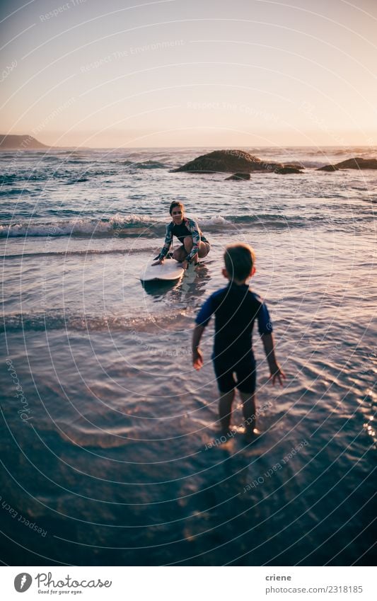 Mother teaching her son surfing with surfboard Lifestyle Joy Happy Relaxation Leisure and hobbies Vacation & Travel Summer Beach Ocean Sports Child Boy (child)