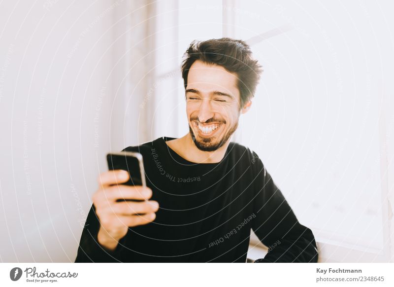 Young man reading text message on his cellphone Lifestyle Luxury Joy Happy Summer Living or residing Flat (apartment) Financial Industry Cellphone Masculine