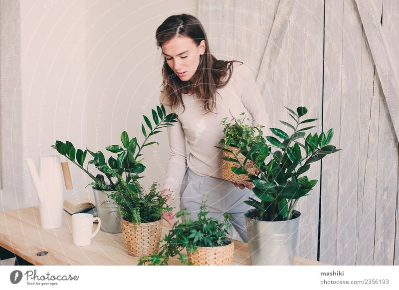 young woman watering flowerpots at home Lifestyle Leisure and hobbies Woman Adults Plant Flower Leaf Watering can Modern Natural Green casual Houseplant