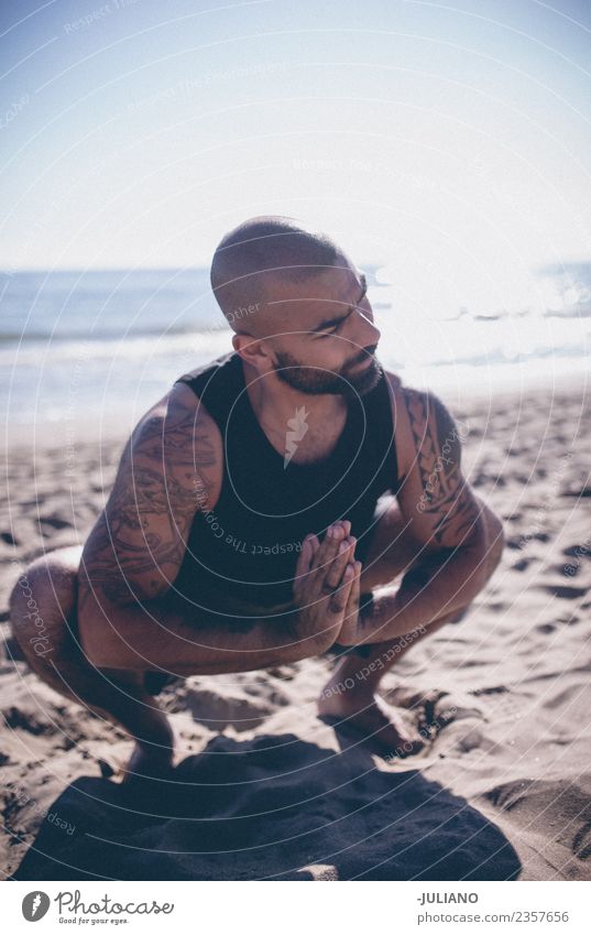 Young sports man is doing yoga for preparation of his workout Lifestyle Happy Beautiful Body Wellness Relaxation Meditation Yoga Beach Sand Exterior shot