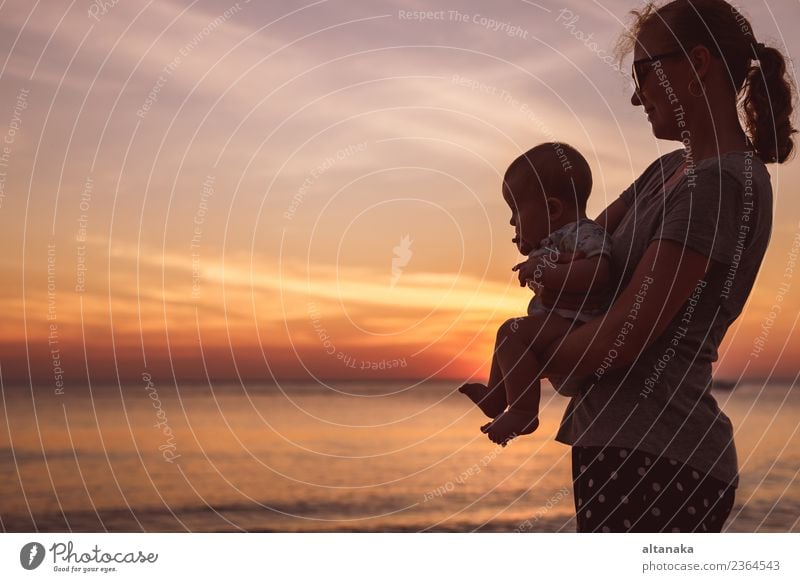 Mother and baby son standing on the beach at the sunset time. Lifestyle Joy Happy Beautiful Leisure and hobbies Playing Vacation & Travel Freedom Summer Sun