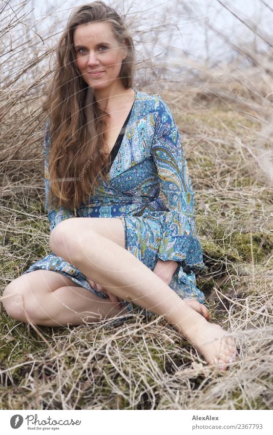 young woman in summer dress sits among bushes and grass barefoot in nature Lifestyle Joy pretty Body Harmonious Trip Adventure Young woman Youth (Young adults)