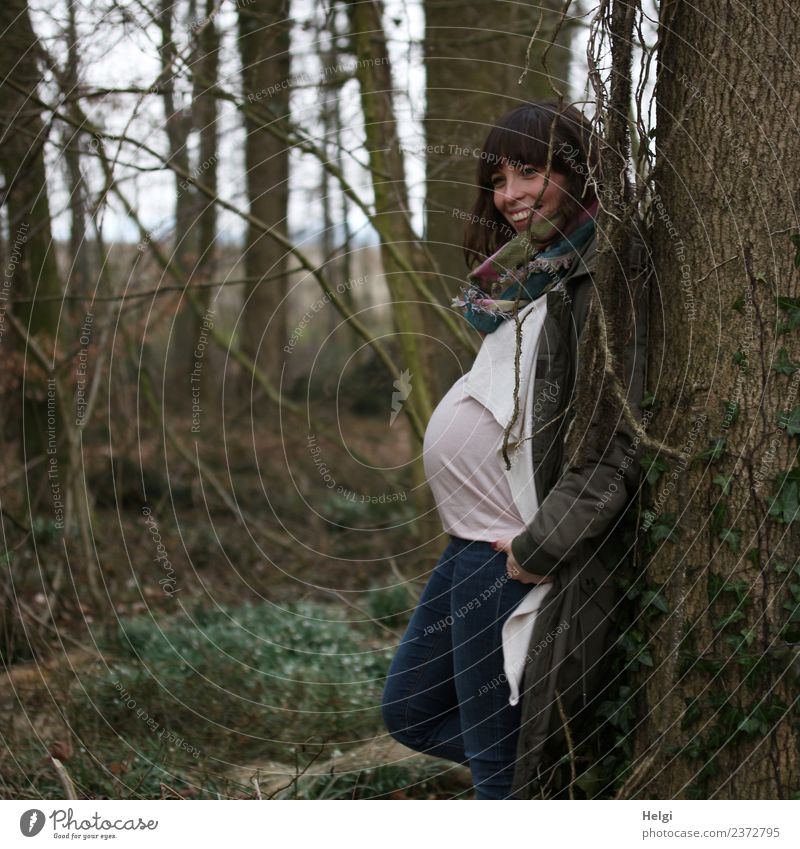 young pregnant woman stands smiling in half profile at a tree Human being Feminine Young woman Youth (Young adults) Adults 1 30 - 45 years Nature Tree Forest