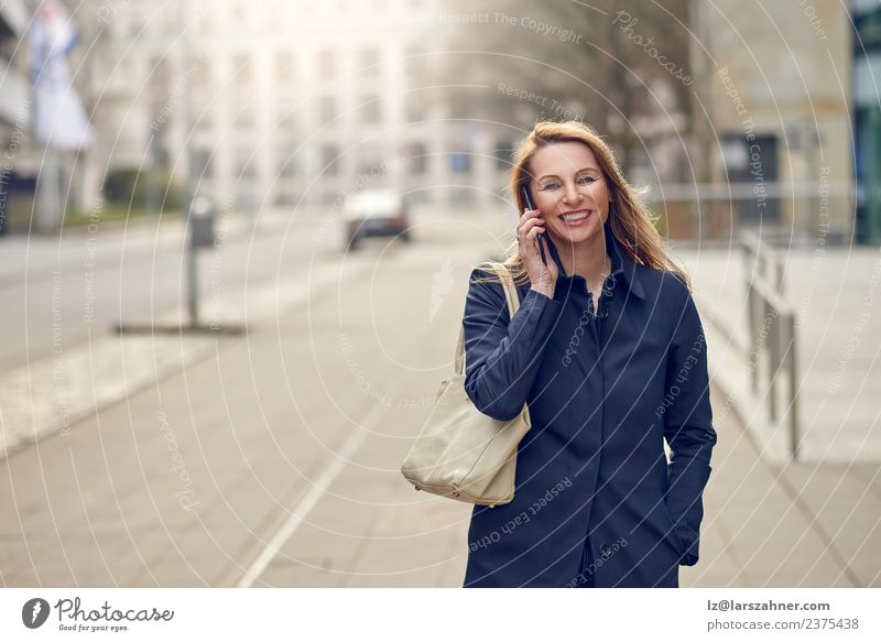 Attractive blond woman chatting on her smartphone Happy Face Business To talk Telephone Cellphone PDA Technology Woman Adults 1 Human being 45 - 60 years Street
