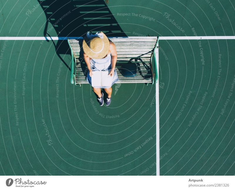 An aerial view of young woman reading a book Book Aircraft Bag Reading Reader Hat Bench Shadow Drone Tennis court Exterior shot Sunset Summer Sunbeam