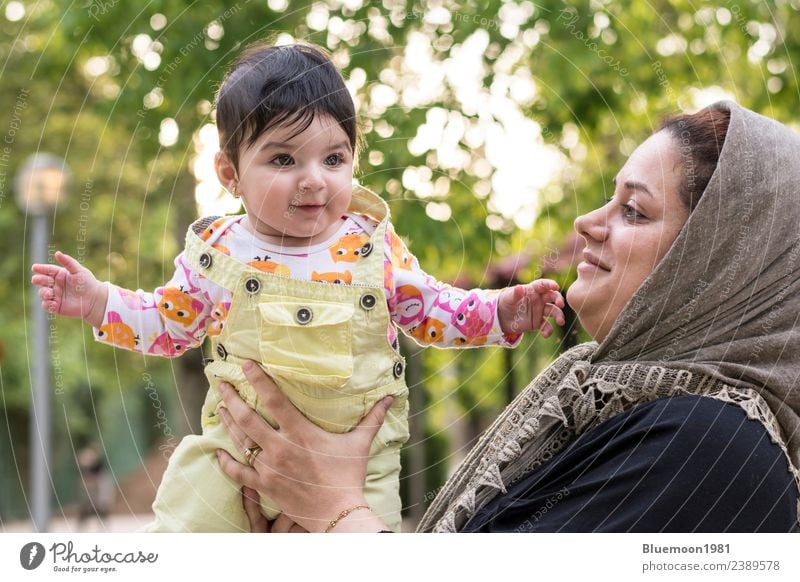 Muslim mother holding a little baby by arms in outdoor area Lifestyle Joy Beautiful Healthy Sun Child Human being Baby Girl Young woman Youth (Young adults)