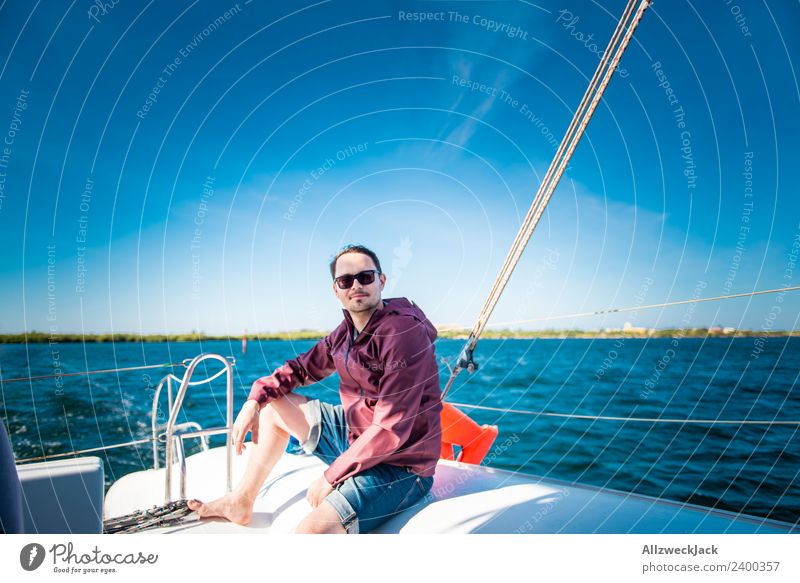 young man sits on a sailboat on the sea Day 1 Person Portrait photograph Young man Short haircut Sunglasses Water Ocean Sailing Sailboat Maritime Lake Blue sky