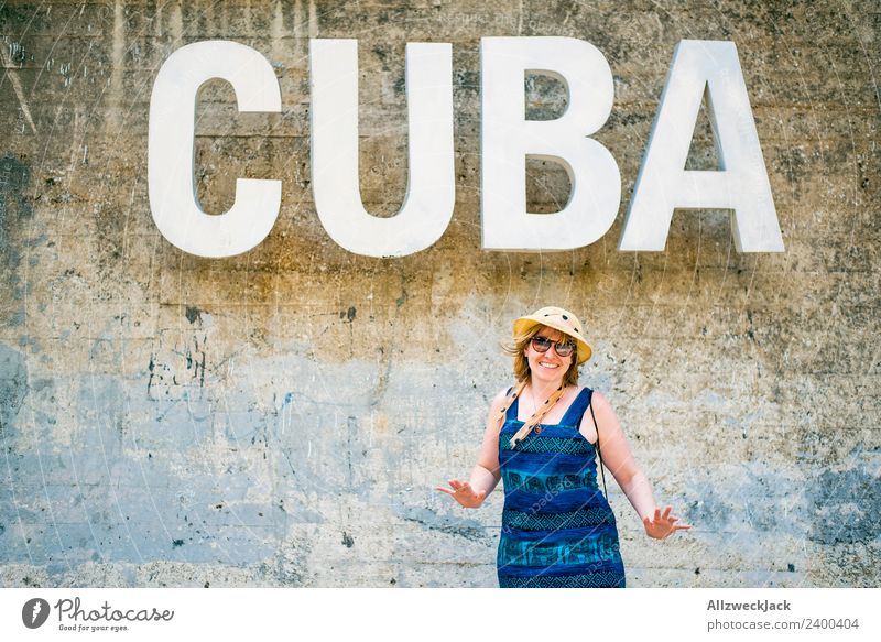 Woman with blue dress and hat before the word CUBA Day Feminine 1 Person Young woman Wall (barrier) Wall (building) Cuba Letters (alphabet) Typography Word