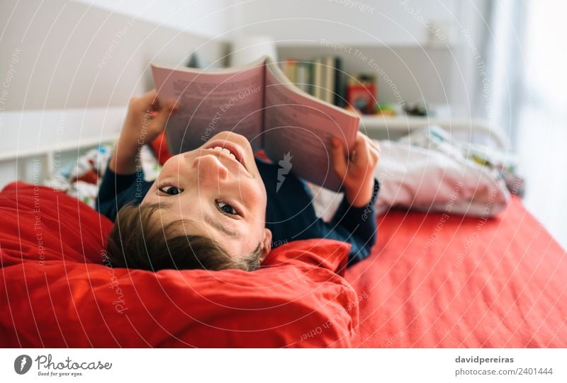 Boy reading book lying on bed Lifestyle Joy Happy Beautiful Calm Leisure and hobbies Reading Bedroom Child Human being Boy (child) Man Adults Culture Book Toys