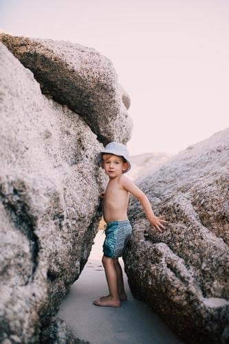 little caucasian boy climbing between big rocks at the beach Summer Beach Climbing Mountaineering Child Toddler Boy (child) Infancy Warmth Rock Swimming trunks