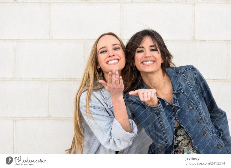 Two beautiful girls blowing a kiss on urban wall outdoors Lifestyle Style Joy Happy Beautiful Human being Feminine Young woman Youth (Young adults) Woman Adults