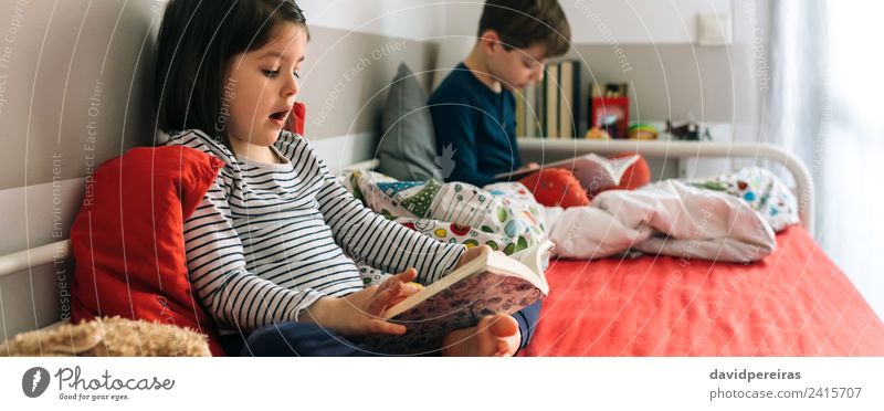 Girl and boy reading a book sitting on the bed Lifestyle Beautiful Calm Reading Bedroom Child School Human being Boy (child) Woman Adults Man Sister Infancy