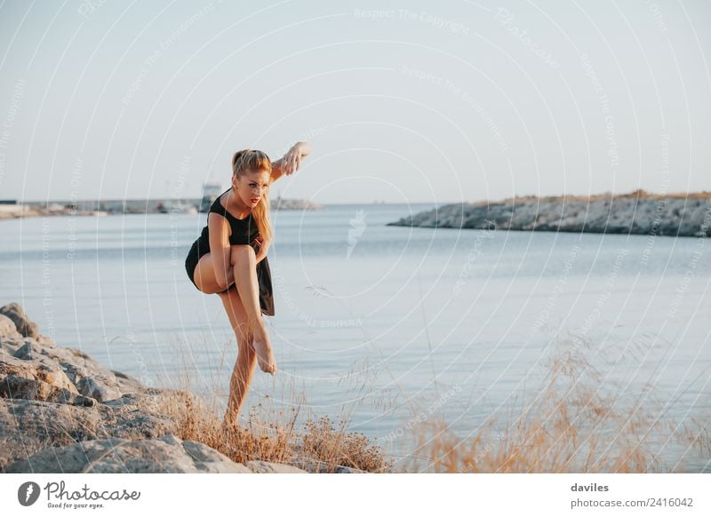 Blonde white woman in black dress performing contemporary dance close to the sea shore. Lifestyle Joy Body Sports Fitness Sports Training Human being