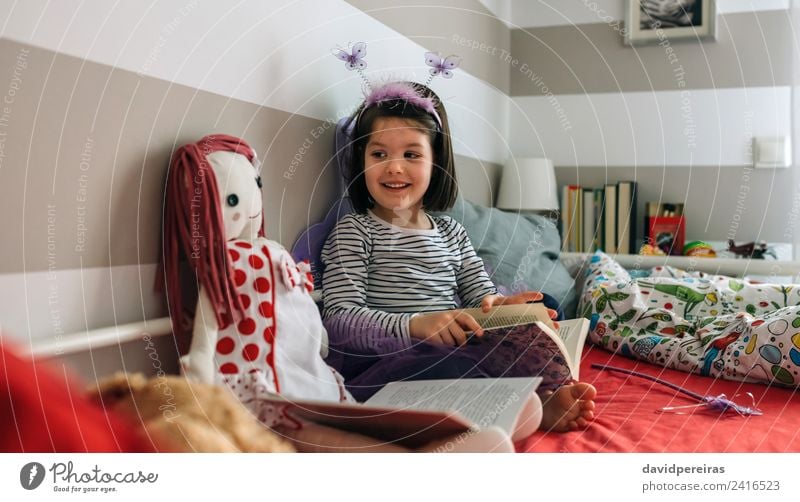 Girl disguised as a butterfly reading with her doll Lifestyle Happy Beautiful Playing Reading Lamp Bedroom Child Human being Woman Adults Friendship Infancy