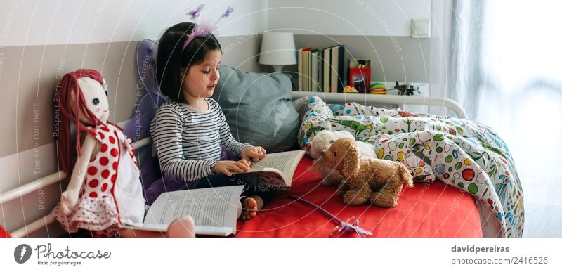 Little girl sitting on bed reading book to her toys Beautiful Playing Reading Bedroom Child Teacher To talk Human being Woman Adults Friendship Book Butterfly