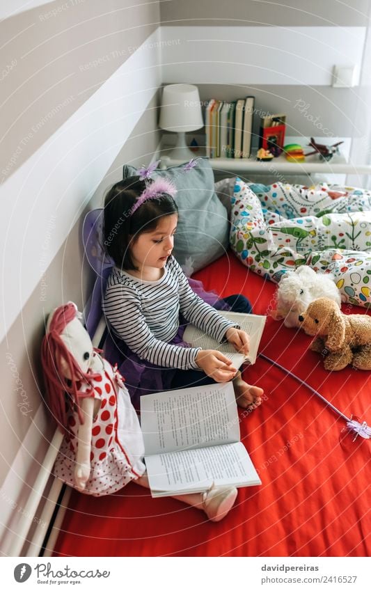 Little girl sitting on bed reading book to her toys Lifestyle Joy Beautiful Playing Reading Bedroom Child Teacher To talk Human being Woman Adults Friendship