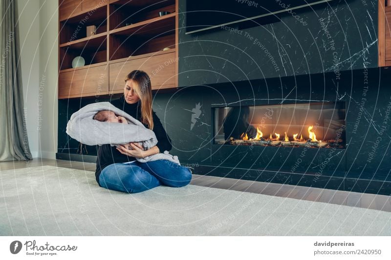 Mother hugging her baby in front of fireplace Lifestyle Happy Beautiful Furniture Fireside Living room Child Human being Baby Woman Adults Family & Relations
