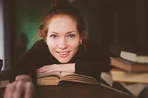 indoor portrait of redhead happy woman learning Lifestyle Relaxation Reading Table Academic studies Woman Adults Book Library Sweater Red-haired Study Dream