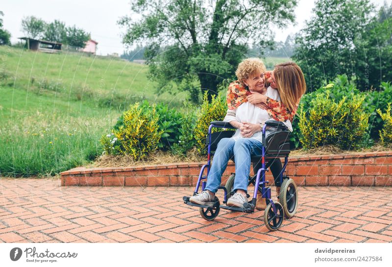 Daughter hugging senior mother in wheelchair Lifestyle Happy Health care Relaxation Garden Human being Woman Adults Mother Grandmother Family & Relations Nature