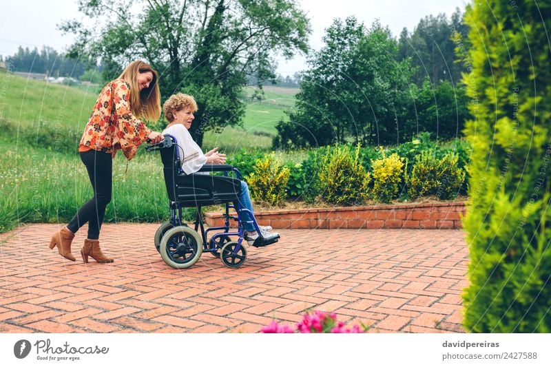 Woman carrying her mother in a wheelchair Lifestyle Happy Health care Relaxation Garden To talk Human being Adults Mother Grandmother Family & Relations Nature