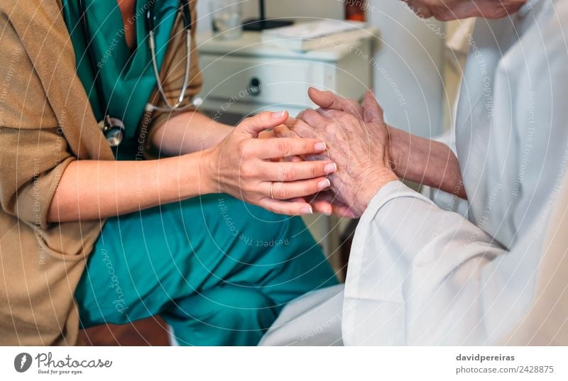 Female doctor holding hands of elderly patient Illness Medication Doctor Hospital To talk Human being Woman Adults Hand Old Authentic Friendliness Trust