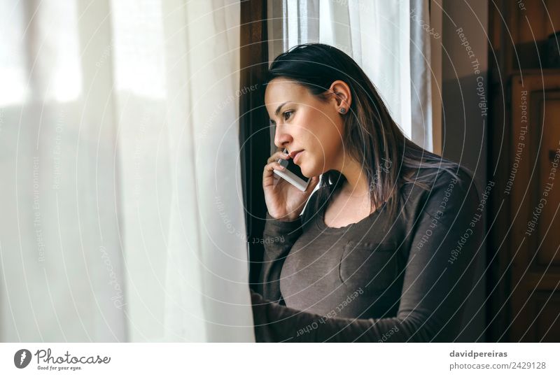 Woman talking cellphone and looking window Lifestyle Beautiful To talk Telephone PDA Human being Adults Sadness Wait Authentic Modern Cute sad Earnest mobile