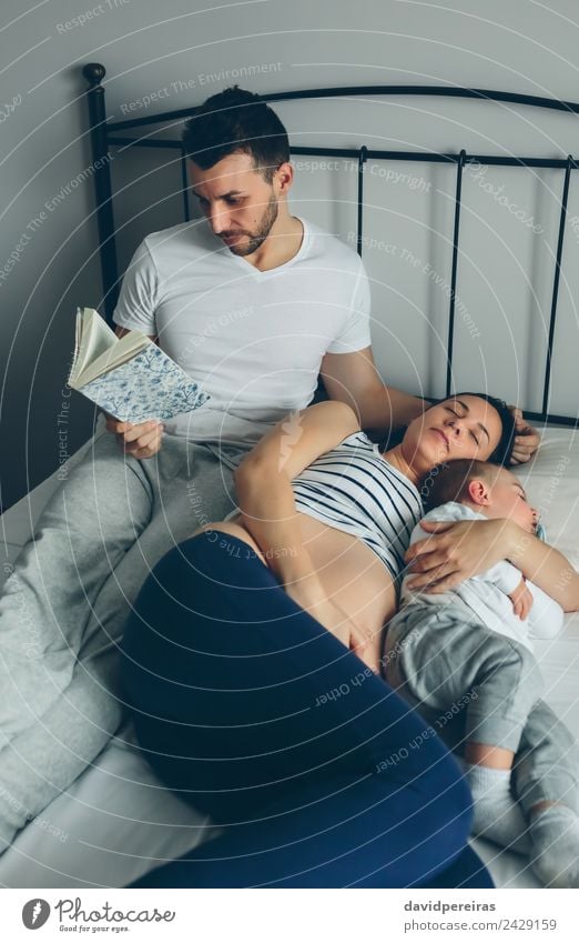 Man reading with pregnant wife and son sleeping Beautiful Relaxation Reading Bedroom Child Human being Baby Toddler Woman Adults Parents Mother Father