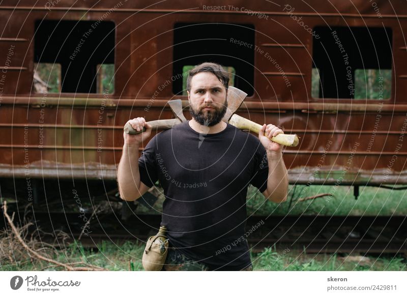 bearded man huntsman with two axes stands near a rusty train Face Wellness Relaxation Leisure and hobbies Vacation & Travel Tourism Summer Summer vacation