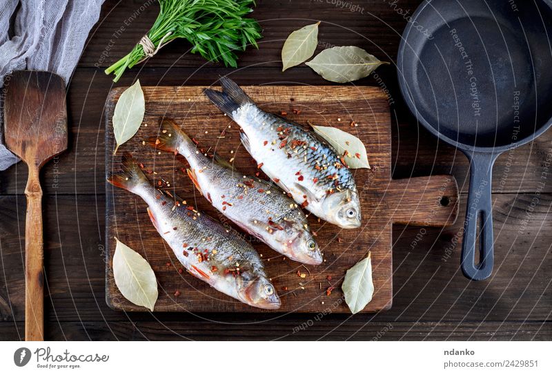 fish on a brown wooden board Fish Seafood Herbs and spices Nutrition Dinner Diet Pan Table Animal River Wood Dark Fresh Above Retro Brown Black Perches