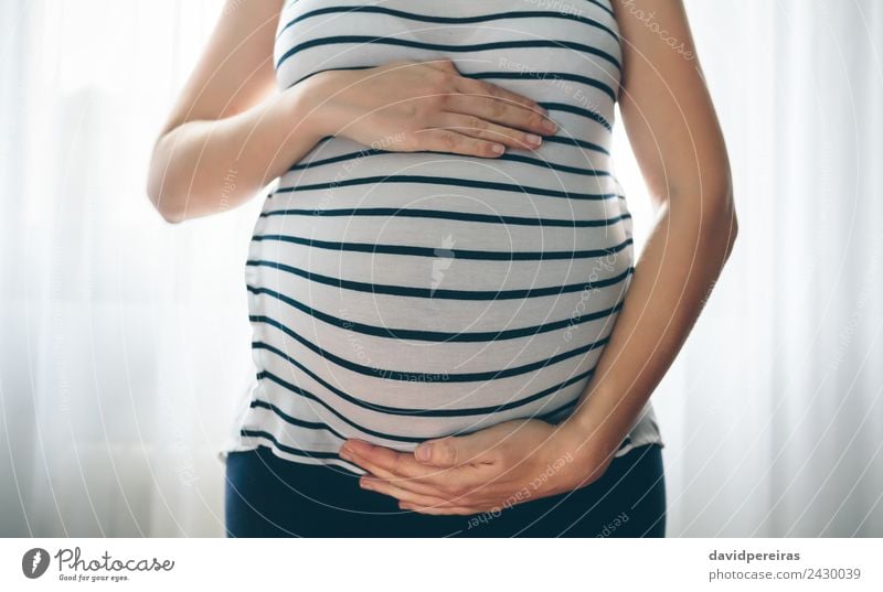Pregnant woman holding her tummy Lifestyle Bedroom Parenting Human being Baby Woman Adults Parents Mother Hand Love Wait Authentic Happiness Serene Hope