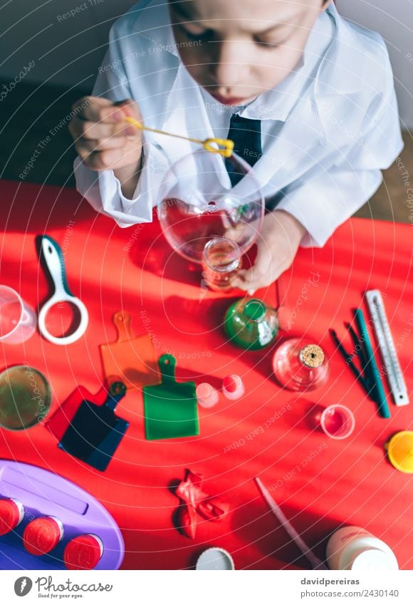 Kid doing soap bubbles over red table Bottle Joy Happy Playing Flat (apartment) Table Science & Research Child School Classroom Laboratory Human being
