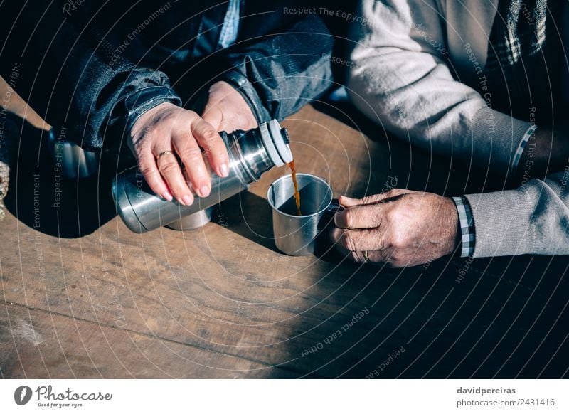 Senior couple hands pouring coffee from thermos Drinking Coffee Tea Lifestyle Relaxation Leisure and hobbies Table Human being Woman Adults Man Couple Hand Wood