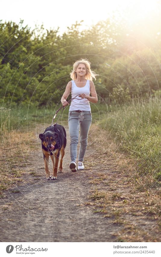 Happy middle-aged woman walking wiht her dog Lifestyle Beautiful Summer Woman Adults Friendship 1 Human being 45 - 60 years Nature Animal Warmth Grass Park
