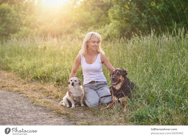 Blond woman with her two dogs in the countryside Happy Face Summer Woman Adults Friendship 1 Human being 45 - 60 years Animal Warmth Grass Meadow Blonde Pet Dog