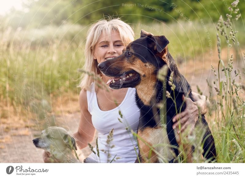 Pretty blond woman with her two dogs Happy Face Summer Woman Adults Friendship 1 Human being 45 - 60 years Animal Warmth Grass Meadow Blonde Pet Dog Smiling