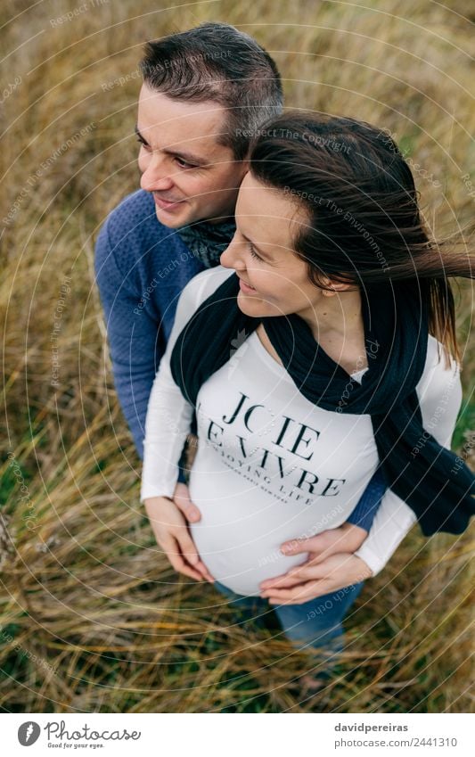 Pregnant with partner hugging and holding belly Lifestyle Happy Beautiful Human being Woman Adults Man Mother Couple Nature Landscape Wind Grass Meadow Aircraft