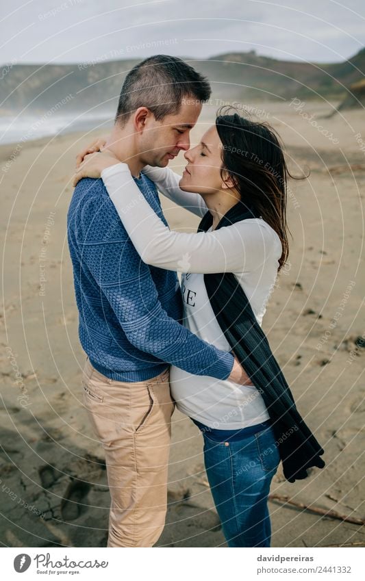 Pregnant woman hugging partner on the beach Lifestyle Happy Relaxation Beach Ocean Winter Human being Baby Woman Adults Man Parents Mother Father