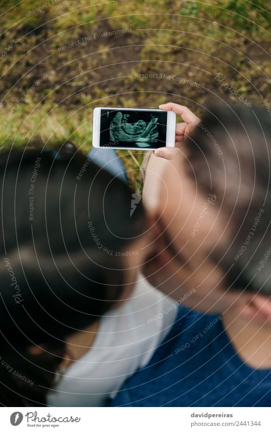 Pregnant looking ultrasound on the mobile with her husband Lifestyle Feasts & Celebrations PDA Technology Human being Baby Woman Adults Man Parents Mother