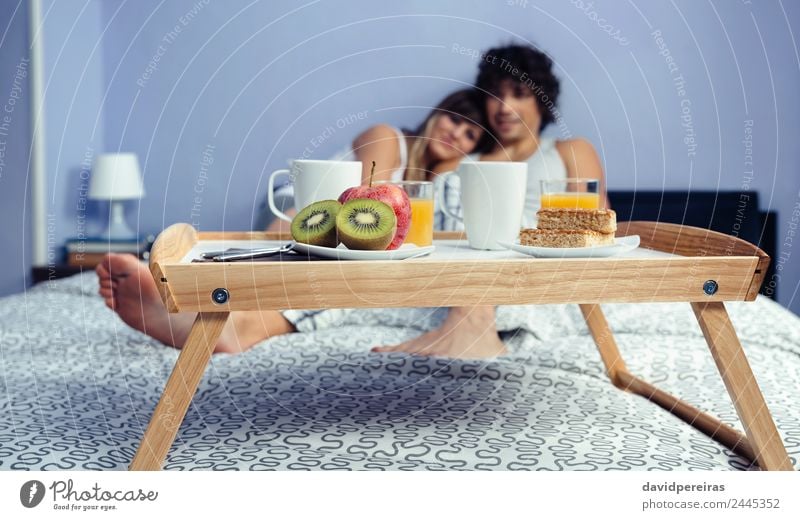 Healthy breakfast on tray and couple lying in background Fruit Apple Breakfast Juice Coffee Lifestyle Happy Beautiful Relaxation Leisure and hobbies Bedroom