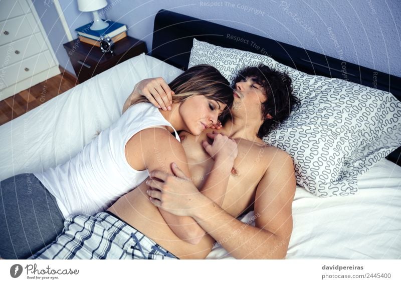 Young couple in love embracing lying over a bed Lifestyle Happy Beautiful Relaxation Bedroom Woman Adults Man Family & Relations Couple Love Sleep Sex Dream