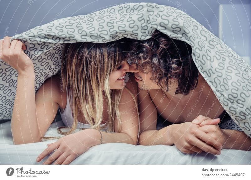 Happy young couple in love kissing under duvet cover Lifestyle Beautiful Relaxation Bedroom Woman Adults Man Family & Relations Couple Kissing Love Sex