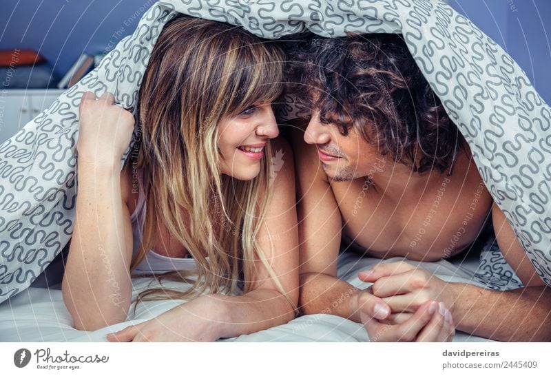Happy young couple in love smiling under duvet cover Lifestyle Beautiful Relaxation Bedroom Woman Adults Man Family & Relations Couple Kissing Smiling Love Sex
