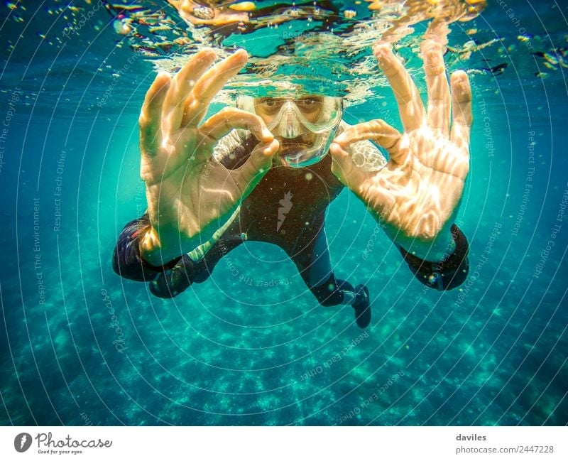 Underwater portrait of man diving in the sea, looking at camera and doing "ok" sign with two hands. Lifestyle Joy Leisure and hobbies Vacation & Travel Summer