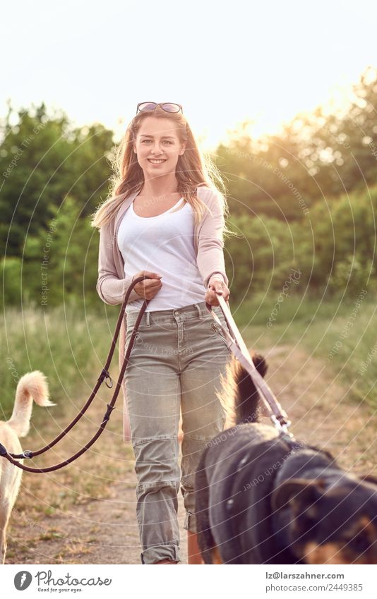 Smiling pretty blond woman walking her two dogs Lifestyle Happy Beautiful Summer Woman Adults Friendship 1 Human being 18 - 30 years Youth (Young adults) Nature