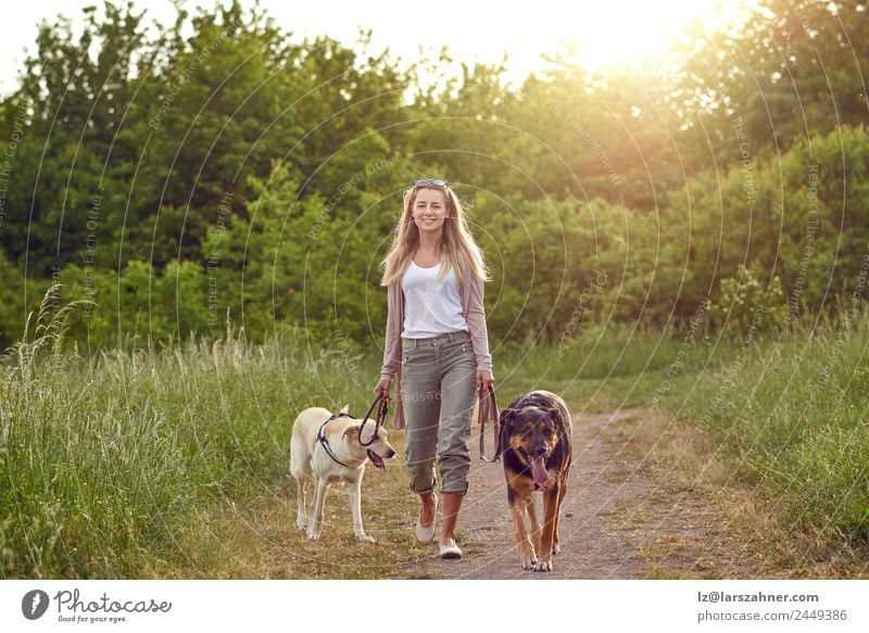 Happy young woman walking wiht her dogs Lifestyle Beautiful Summer Woman Adults Friendship 1 Human being 18 - 30 years Youth (Young adults) Nature Animal Warmth
