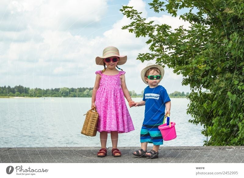 A boy and a girl in toddlerhood are standing on a log in summer clothes, looking to the left Beach Human being Baby Family & Relations Relaxation