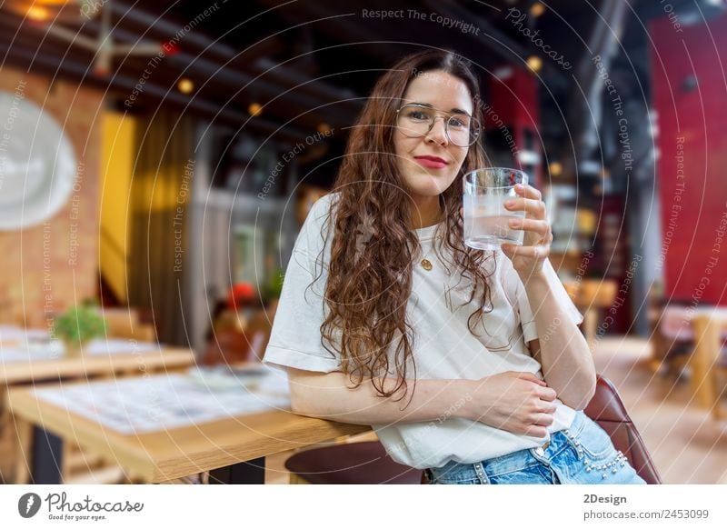 Pretty young woman holding a glass of water Breakfast Beverage Drinking Coffee Lifestyle Happy Beautiful Health care Relaxation Summer Chair Table Restaurant